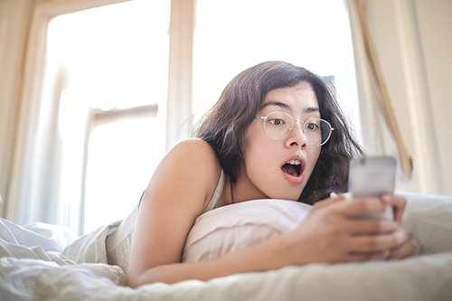 500-woman-lying-on-bed-holding-smartphone-3807535.jpg